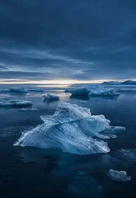 iPhone Duo arctic shore wallpaper for the cover screen, An arctic shoreline at blue hour, dark water, pale ice blocks, and a low silver horizon. 1398x2034 px
